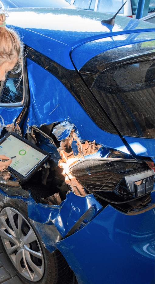 Auf dem Bild ist eine Person zu sehen, die mit einem Tablet in der Hand den Schaden an einem Fahrzeug überprüft. Der Tablet-Bildschirm zeigt die CombiPlus Online-Oberfläche, auf der der Schadenfall erfasst und verwaltet wird. Der Schaden am hinteren Bereich des Fahrzeugs ist deutlich sichtbar, und die Person nutzt die CombiPlus Online-Plattform zur Schadenbewertung und Dokumentation des Vorfalls.